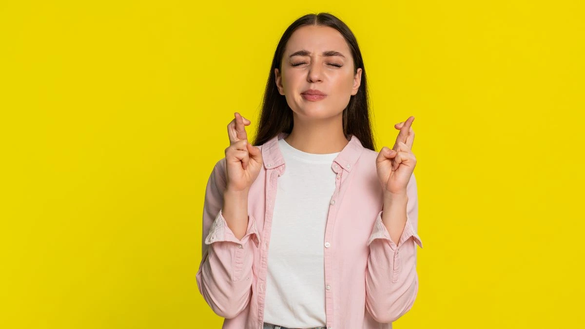 Kobieta z zaciśniętymi palcami i zamkniętymi oczami &ndash; intencja oparta na napięciu i oczekiwaniu efektu