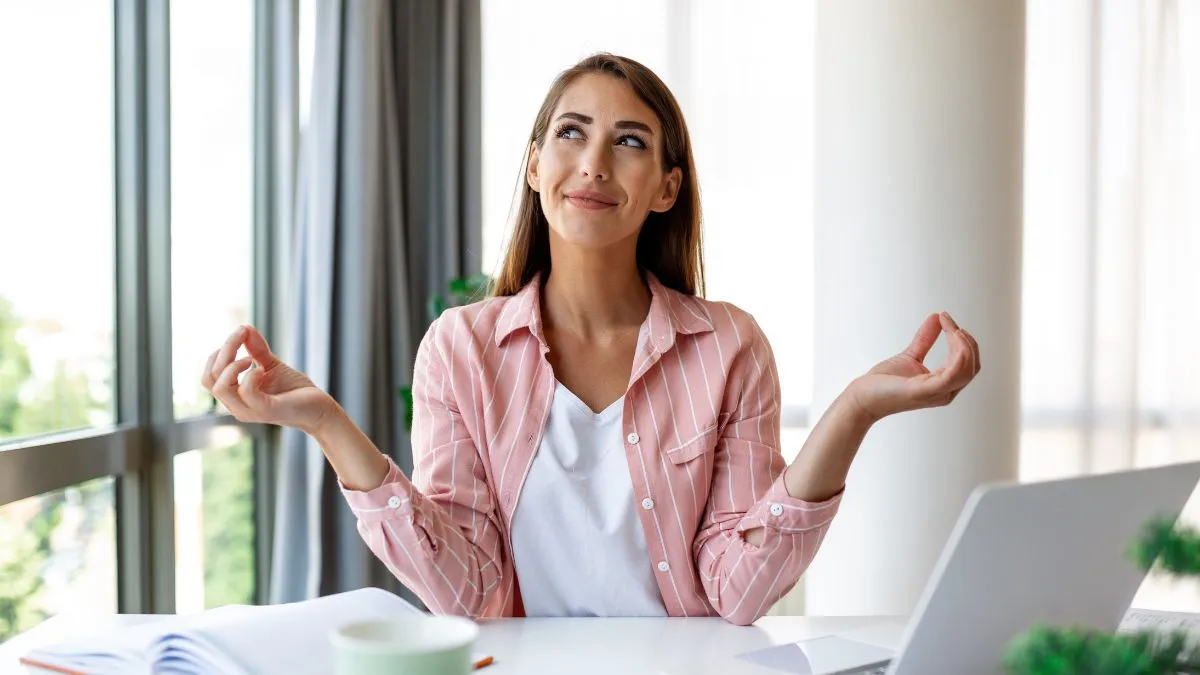 Kobieta siedzi przy biurku i uspokaja się, wykonując prostą technikę