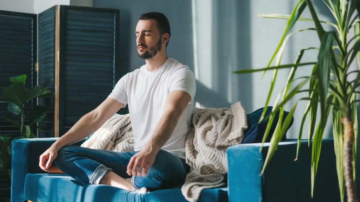 Mężczyzna praktykujący medytację Oddech Życia i spokojny oddech na kanapie.