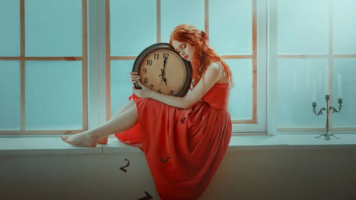 Kobieta w czerwonej sukni obejmująca duży zegar &ndash; symbol zatrzymania w przeszłości i emocjonalnego przywiązania do dawnych relacji